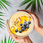 hands displaying a mango smoothie bowl